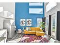 Bright living space with a blue accent wall, a mustard colored couch, and tall windows providing natural light at 3120 Godby Rd, Atlanta, GA 30349