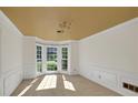 Sunlit dining room with a bay window, neutral carpet, crown molding, and classic wainscoting at 1411 Blackland Trl, Lawrenceville, GA 30043