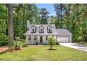 Landscaped front yard view of a Cape Cod-style home with dormer windows and a covered front porch at 944 Pine Ridge Dr, Stone Mountain, GA 30087