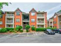 Brick condo building featuring a balcony and reserved parking spaces, surrounded by lush greenery at 4106 Chastain Park Ne Ct, Atlanta, GA 30342
