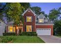 Well-maintained two-story brick home featuring manicured lawn and a two-car garage at twilight at 440 Laurian Nw Way, Kennesaw, GA 30144