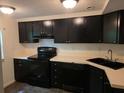 Kitchen featuring black appliances, updated black sink and faucet with matching dark cabinets at 5826 Par Four Ct, Lithonia, GA 30038