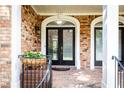 Inviting front porch with double doors, brick floor, overhead light, and black metal railings at 2610 Oglethorpe Ne Cir, Brookhaven, GA 30319
