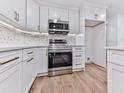 Modern kitchen features stainless steel appliances, white cabinetry, hardwood flooring, and backsplash at 221 Wonewok Dr, Canton, GA 30114