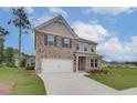 Attractive two-story home with brick and siding, a manicured lawn, and a spacious driveway leading to the garage at 320 Tulip Dr, Covington, GA 30016