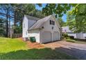 Side view of a charming home with a two-car garage, green lawn, and mature trees at 141 Weatherstone Dr, Woodstock, GA 30188