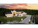 Elegant modern farmhouse with black trim, professional landscaping, and a long driveway highlighted by a colorful dusk sky at 5160 Howard Rd, Cumming, GA 30040
