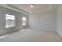 Bright and spacious carpeted main bedroom with tray ceiling and two windows offering natural light at 612 Sidney Ct, Stockbridge, GA 30281