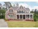 Charming two-story brick home with a welcoming front porch and meticulously manicured lawn at 1073 Sweet Mia Ln, Powder Springs, GA 30127