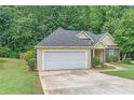 Exterior view of a charming home with an attached garage, green lawn, and manicured shrubbery at 1335 Vine Cir, Mcdonough, GA 30253