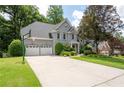 View of a two-story home, two-car garage, long driveway, and green lawn with basketball hoop at 4957 Day Lily Nw Way, Acworth, GA 30102