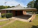 View of the home featuring a large carport, brick siding, and manicured landscaping at 871 Malcom Se St, Conyers, GA 30012