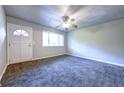 Bright living room with new gray carpet, a ceiling fan, and ample natural light from the large window at 5904 Heatherwood Ln, Riverdale, GA 30296
