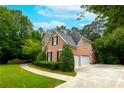 A well-maintained brick house with a driveway and lush green landscaping at 1000 Admiral Xing, Alpharetta, GA 30005