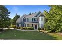 Charming two-story home with blue siding, stone accents, manicured lawn, and mature trees at 1210 Magnolia Park Cir, Cumming, GA 30040