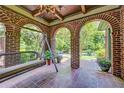 Relaxing brick porch with swing, tiled floor, arched openings, and serene outdoor views at 1356 Emory Ne Rd, Atlanta, GA 30306