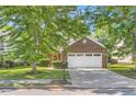 Traditional brick home with a two-car garage, mature trees, and green lawn at 484 Cathedral Dr, Mcdonough, GA 30253