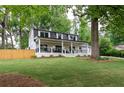 Beautiful white home with black roof, dormer windows, and a spacious front yard surrounded by lush trees at 550 Stewart Nw Ave, Marietta, GA 30064