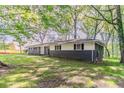 Landscaped home featuring dark brick, bright white siding, and lots of large trees at 545 Fayetteville Rd, Fairburn, GA 30213