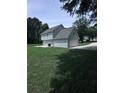 A grassy lawn with a partial view of a two-story home with light blue siding and an attached garage at 1201 Saint Andrews Dr, Auburn, GA 30011