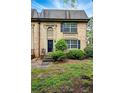 Close-up of a brick townhouse with a black door and manicured bushes at 6980 Roswell Road # A8, Atlanta, GA 30328