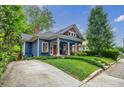 Attractive blue house with charming curb appeal, complemented by green lawn, driveway, and mature trees at 549 Atwood Sw St, Atlanta, GA 30310