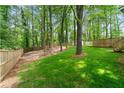 Large, grassy backyard enclosed by a wooden fence with mature trees providing shade and privacy at 2110 Argyle Se Dr, Smyrna, GA 30080