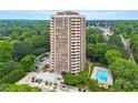 This aerial view shows a brick highrise with a pool and wooded area in a quiet community at 1501 Clairmont Rd # 1213, Decatur, GA 30033