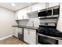 This is a compact kitchen with white cabinets, black countertops, and stainless steel appliances at 1501 Clairmont Rd # 1213, Decatur, GA 30033