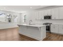 Modern kitchen featuring a large island, white cabinetry, stainless steel appliances, and hardwood floors at 22 Foothills Trl, Sharpsburg, GA 30277