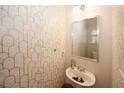 Stylish half-bath showcasing patterned wallpaper, a pedestal sink, and a modern mirror at 10162 Benton Woods Dr, Covington, GA 30014