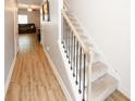 Hallway featuring wood-look flooring, stairs with carpet and iron railing, and access to the living area at 10162 Benton Woods Dr, Covington, GA 30014