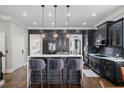 Modern kitchen featuring dark cabinetry, pendant lighting, island with seating, and hardwood floors at 1525 Camden Cove Dr, Cumming, GA 30040