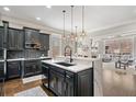 Modern kitchen with black cabinetry, island, and open layout to the living room with fireplace at 1525 Camden Cove Dr, Cumming, GA 30040