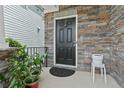 Inviting front door with a stone facade, black door and potted plants on the front porch at 3255 Morgan Rd, Buford, GA 30519