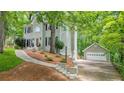 Exterior view showcasing a long driveway leading to a detached garage surrounded by lush greenery at 3267 Standing Peachtree Nw Trl, Kennesaw, GA 30152