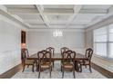 Spacious dining room featuring a coffered ceiling, chandelier, and an oversized dark wood dining table with seating at 4240 Summer Breeze Way, Buford, GA 30518