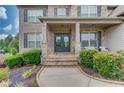 Inviting covered porch entrance features stone accents, double doors, and meticulously landscaped front yard at 4240 Summer Breeze Way, Buford, GA 30518