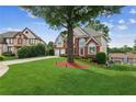 Expansive green front yard featuring a mature tree, long driveway, and neighboring homes at 1316 Wind Chime Ct, Lawrenceville, GA 30045