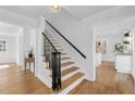 Elegant staircase with hardwood steps and a black railing, illuminated by modern light fixture at 5143 Meadowlake Ln, Dunwoody, GA 30338