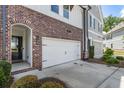 Exterior home view of a townhome, showcasing brick accents, arched entryway, and a convenient attached garage at 408 Niles Ct, Marietta, GA 30060