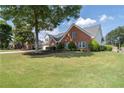 Brick home featuring a manicured lawn, mature trees, and charming curb appeal in a serene suburban setting at 3027 Biltmore Woods Dr, Buford, GA 30519