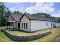 This home features a covered patio with a stone retaining wall and lush green lawn at 532 Rockbridge Rd, Lilburn, GA 30047