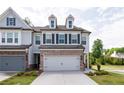 Beautiful townhome exterior with a two-car garage, a brick facade, and a well-maintained lawn at 668 Isom Walk, Suwanee, GA 30024