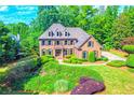 Charming two-story brick home with manicured landscaping, lush green lawn, and mature trees at 2111 Broadfield Run, Duluth, GA 30097