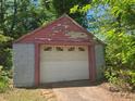 Detached garage featuring a white garage door with a red trim and a blue block foundation at 25 Candler Se Rd, Atlanta, GA 30317