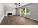 Cozy living room with fireplace, neutral paint, wood-look floors, and a large sunny window at 2923 Akron St, East Point, GA 30344
