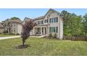 Two-story home with a manicured lawn and a mature tree in the front yard, showcasing the charming facade at 7820 Bristol Valley Dr, Cumming, GA 30028