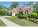 Beautifully landscaped brick home with mature trees, green lawn and attached garage at 1010 Graystone Xing, Alpharetta, GA 30005