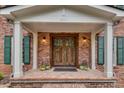 Inviting entryway with a brick porch, wood double doors, and classic white columns at 2592 River Oak Dr, Decatur, GA 30033